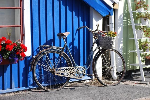 Sykkel med blomsterkurv mot blå trevegg