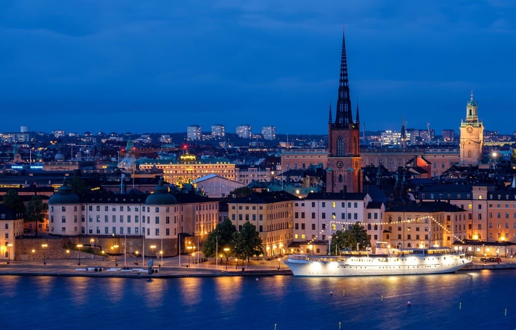 Stockholm vid Riddarfjärden i skymning med upplysta hus och båtar